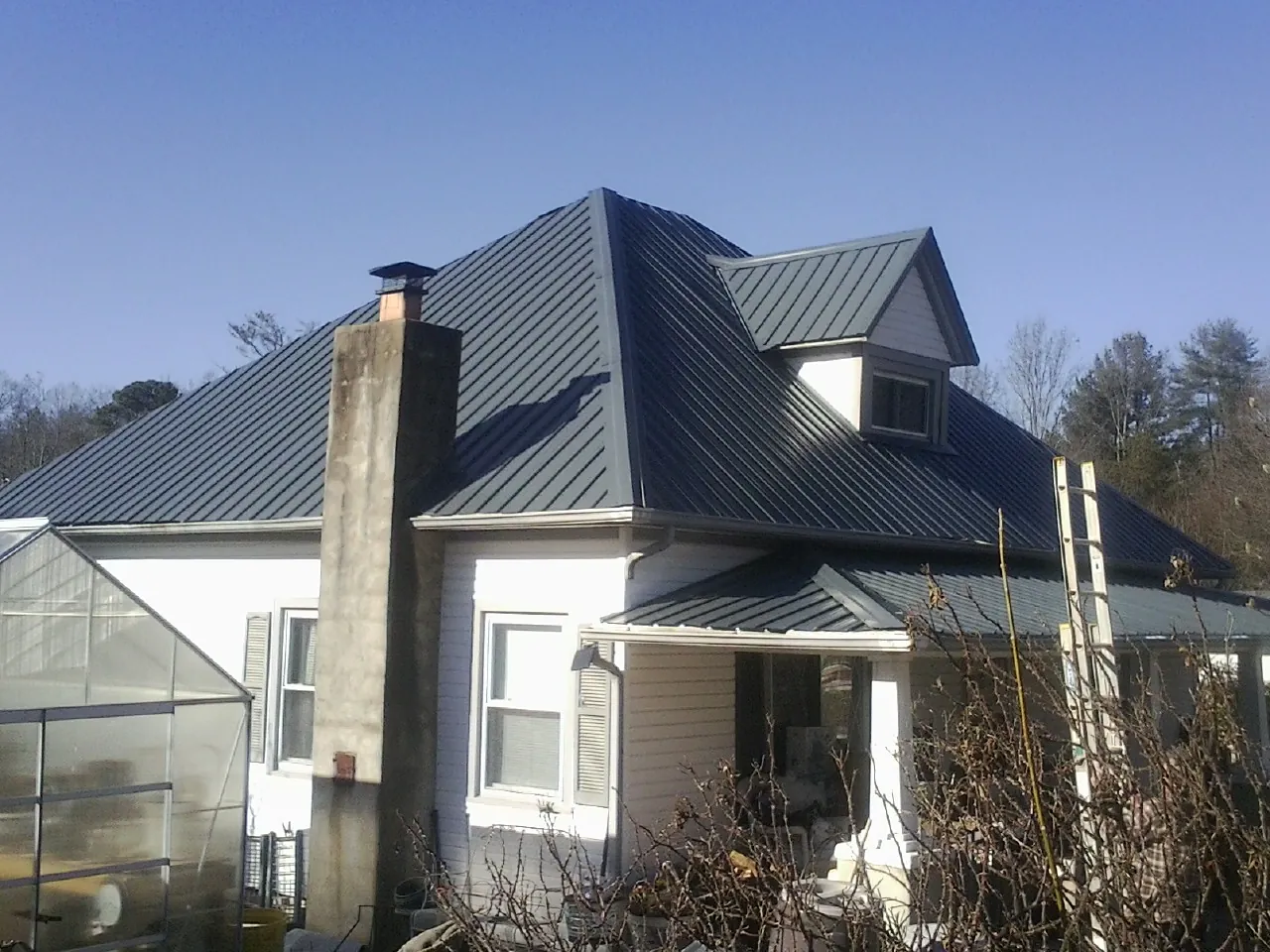 Dark blue standing seam metal roof on a white farmhouse with dormer — Slate & Tile Roof Repair by Roofing Brothers in Bloxom