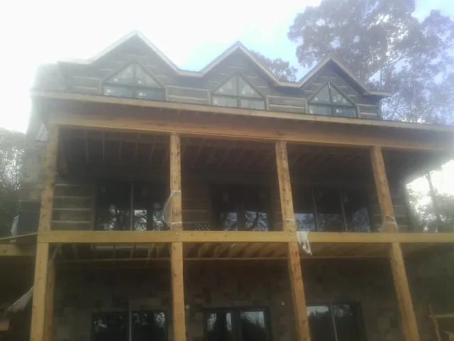 Dormers and porch framing on a large log home under construction — Roof Coating work by our crew in Bloxom
