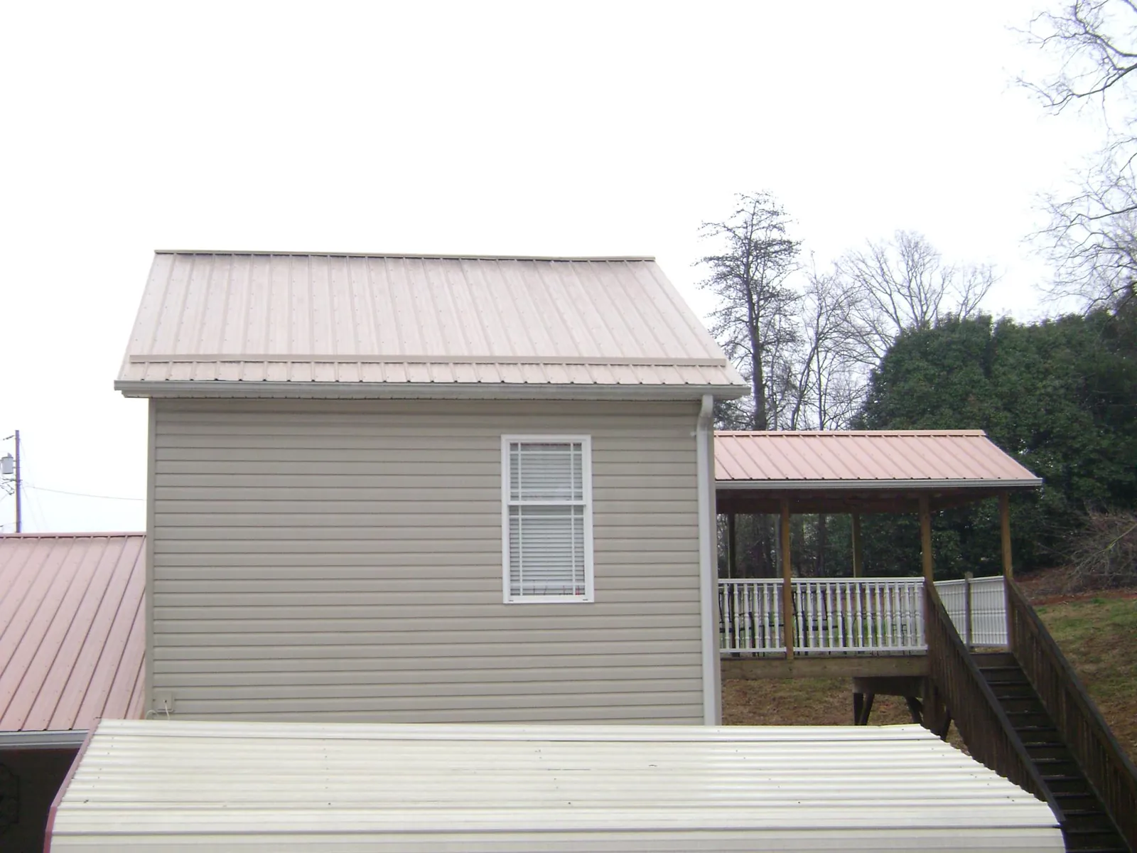 Tan metal roofs on a two story addition and attached porch, from a Roof Replacement job in Bloxom