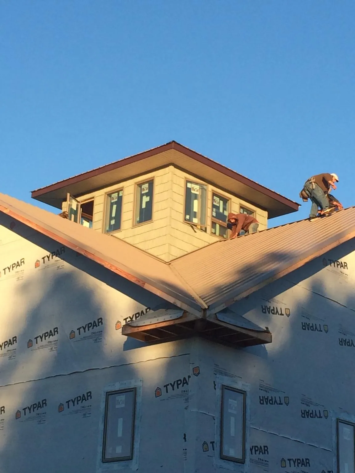 Roofers working around a rooftop cupola on a new metal roof at sunset — Roof Waterproofing in Bloxom by Roofing Brothers